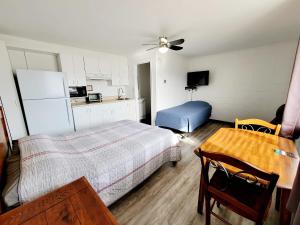 1 dormitorio con cama, mesa y cocina en Hébergement du plateau, en Dolbeau