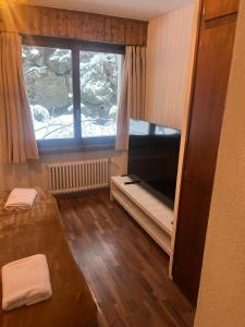 Zimmer mit einem großen Fenster und einem TV in der Unterkunft Auberge de l'Ours in Les Collons