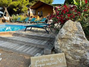 una terraza de madera con un cartel junto a una piscina en DOMAINE DU CHENE, en Campagnan