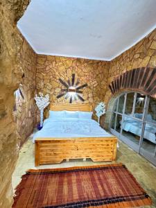 1 dormitorio con cama y pared de piedra en DanaBlack iris house, en Dana