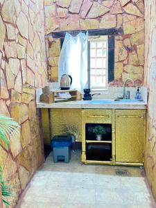 eine Küche mit einer Theke und einem Waschbecken in einer Steinwand in der Unterkunft DanaBlack iris house in Dana