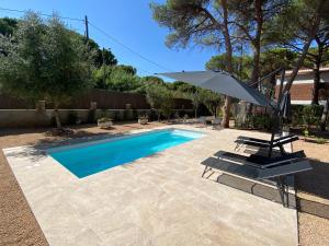 a swimming pool with an umbrella and a chair at Fantastica casa con piscina a 5 min a pie del mar - Sorramar in Gavà