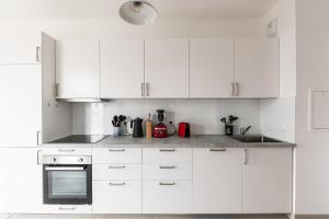 una cocina blanca con armarios y electrodomésticos blancos en Bright T5 with terrace in Saint-Ouen - Welkeys, en Saint-Ouen
