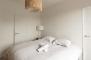 Una cama blanca con dos rollos de papel higiénico. en Bright T5 with terrace in Saint-Ouen - Welkeys, en Saint-Ouen