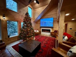 una sala de estar con un árbol de Navidad y una chimenea en Redwood - Lakeside Cabin, en Bradford