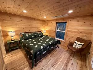 1 dormitorio en una cabaña de madera con 1 cama y 1 silla en Redwood - Lakeside Cabin, en Bradford