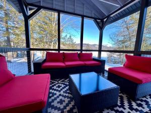 un porche cubierto con sofás rojos y una mesa en Redwood - Lakeside Cabin, en Bradford