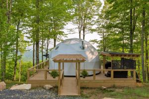 a yurt with a wooden deck in the woods at Tranquility Luxe Dome - Hot Tub & Luxury Amenities in Swiss