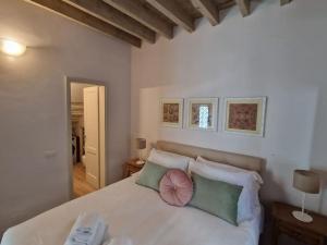 Un dormitorio con una cama blanca con almohadas verdes y rosas en Angolo al Giardino delle Rose, en Florencia