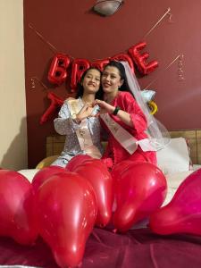 two women are sitting on a bed with balloons at Horizon Homes - Sauraha Chitwan in Sauraha