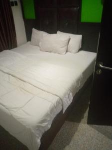 uma cama com lençóis brancos e almofadas num quarto em light house hotel lekki phase 1 em Lekki