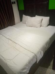 uma cama com lençóis brancos e almofadas num quarto em light house hotel lekki phase 1 em Lekki