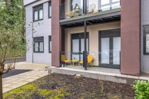 a house with glass doors and yellow chairs on a patio at Fabulous, Modern Apartment, Solihull in Olton