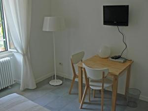 Cette chambre comprend une table, une télévision et un lit. dans l'établissement B&b Il Sampietrino Dei Cavalleggeri, à Rome 2 autres photos