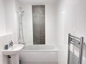a white bathroom with a sink and a bath tub at Queens House City Centre Apartments in Sheffield