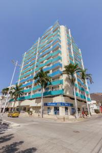 a tall building with palm trees in front of it at Apartamento El Rodadero Cerca al Mar in Santa Marta