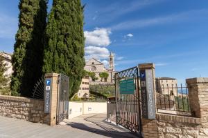 a gate to a building with a church in the background at Helios Assisi in Assisi