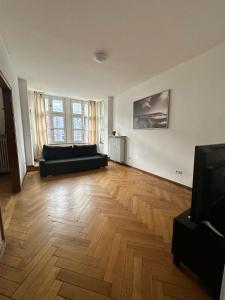 a living room with a black couch and a wooden floor at dreams Düsseldorf in Düsseldorf