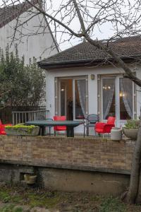 un patio con sillas rojas y una mesa verde en LE COTEAU Pavillon au calme 2 chambres 4-5 personnes, en Savigny-sur-Orge