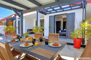 a wooden table with plates of food on a patio at La Maison Du Bonheur - Villa moderne avec SPA in Saint-Joseph