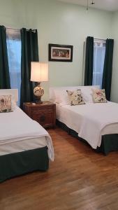 Josephine's Bed & Breakfast في Titusville: سريرين في غرفة مع ستائر خضراء