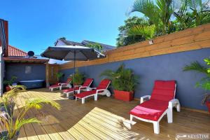 a patio with red chairs and an umbrella at La Maison Du Bonheur - Villa moderne avec SPA in Saint-Joseph