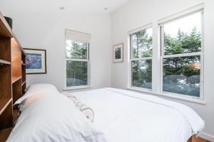 two beds in a white room with windows at Lodging at Goose Cove Retreat - Trinity, Newfoundland in Trinity