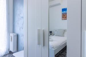 biała sypialnia z łóżkiem i lustrem w obiekcie HouSmart Galeotti 16 w Bolonii
