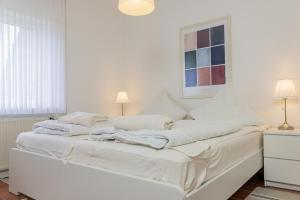 een wit bed met witte lakens en kussens erop bij Haus Harle 50203 Ferienhaus Harle 1 in Harlesiel