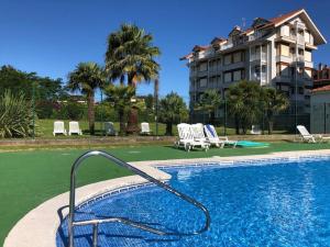 a swimming pool with chairs and a building at Apartamentos Zenit Mar in Noja
