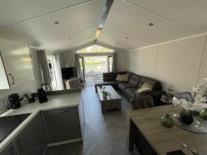 a kitchen and living room with a couch and a table at Gloednieuw luxe chalet met infraroodsauna in Hoenderloo