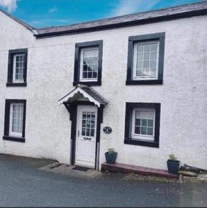 a white house with black windows and a door at Mews Cottage in Appleby