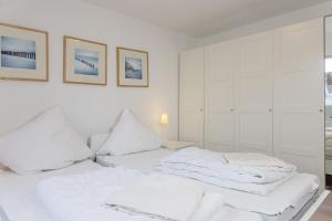 a white bedroom with two beds with white pillows at Haus Harle 50202 Ferienwohnung Harle 2 in Harlesiel