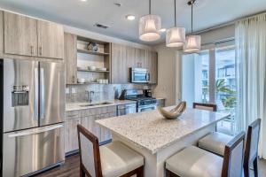 a kitchen with a large island with chairs and a large window at Texas Two Step in Rosemary Beach