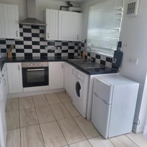 a kitchen with a washing machine and a washer at Exquisite 3-Bed Royal Pearl Home in Greater London in Thamesmead