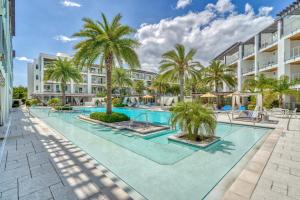 a swimming pool with palm trees in front of a building at Texas Two Step in Rosemary Beach