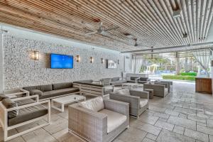 a living room with couches and a tv on a wall at Texas Two Step in Rosemary Beach