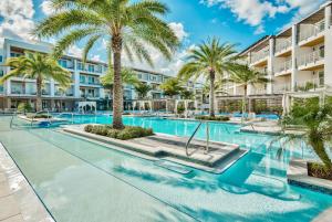 a swimming pool with palm trees in front of a building at the Pointe Unit 326 in Rosemary Beach