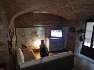 a woman sitting in a living room watching a tv at Bella Toscana in Pomarance