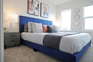 - un lit bleu avec une tête de lit bleue dans une chambre dans l'établissement Stylish Home with 3 King Beds,Garage,Disney+, à Edmonton
