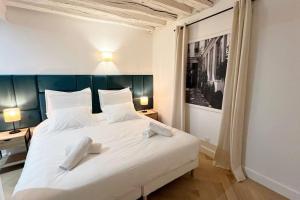 a bedroom with a white bed with two white towels on it at Magnificient Parisian Flat - Parisian heart in Paris