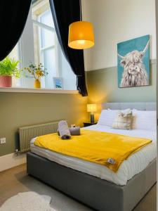 a bedroom with a large bed with a yellow blanket at The Old Schoolhouse, Kinross in Kinross