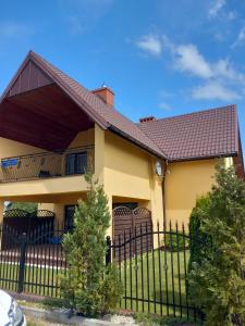 a yellow house with a black fence at JARZĘBINOWA 7 in Rowy