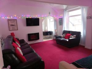 a living room with two leather couches and a tv at The Coach House Apartment in Lytham St Annes