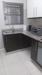 a kitchen with a sink and a microwave at Urban Studio Pvt Appartment in Durban