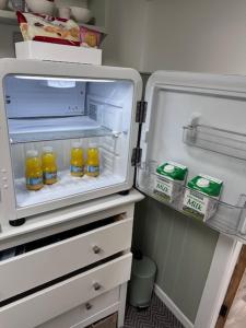 an open refrigerator with bottles of orange juice in it at The Little Garden Hideaway with Stunning Sea Views and Garden in Holyhead