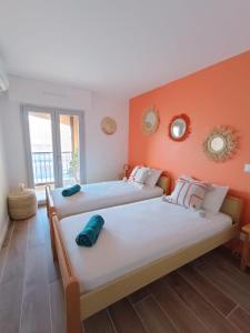 two beds in a room with orange walls at La Palmeraie 2 chambres in Sainte-Maxime