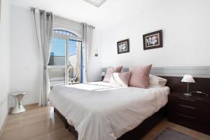 a bedroom with a bed with white sheets and pink pillows at La caleta in La Cala de Mijas