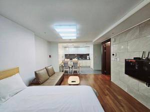 um quarto com uma cama, um sofá e uma cozinha em Ciel de Mer em Busan