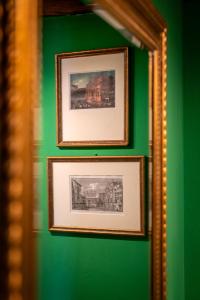 two framed pictures hanging on a green wall at Palazzo San Luca in Venice